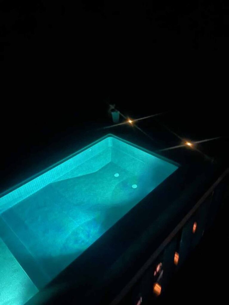 A pool installed by our team shown at night, lit from beneath by lights in the pool