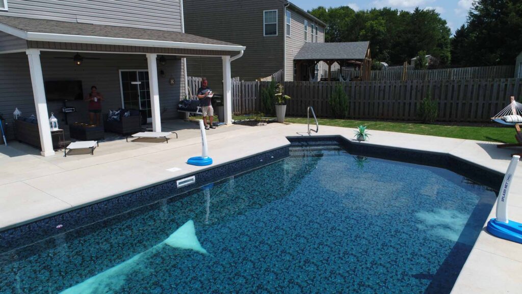 An inground pool shines in the afternoon sunlight.