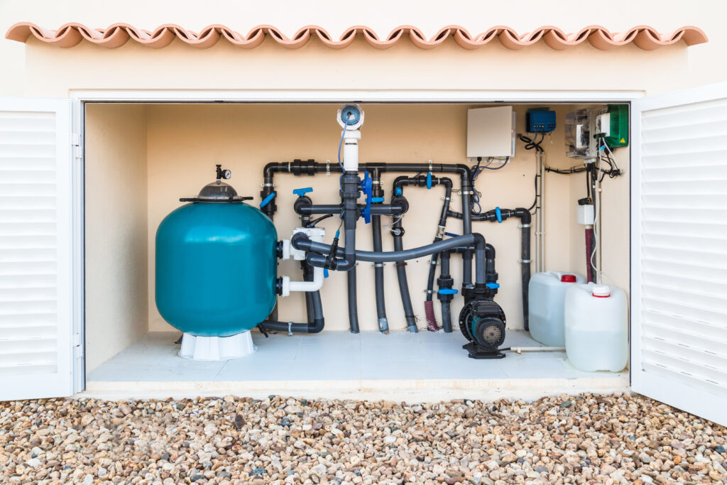 Open outdoor equipment cabinet showing a large blue pressure tank and complex network of black pipes, valves, and filters inside.