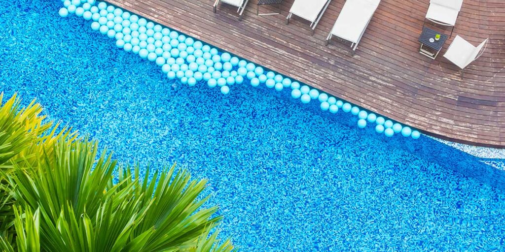 Overhead view of a completed vinyl liner swimming pool with clear blue water and a wooden deck for installation guides.
