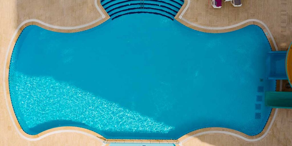 Aerial top-down view of a newly installed fiberglass swimming pool filled with clear blue water and surrounded by patio coping.